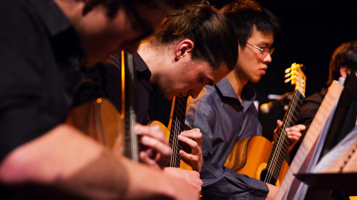 photo of young men playing guitars
