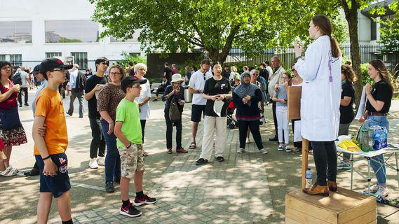 photo of a womenin lab coat speaking outside to a group of people